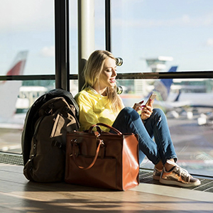 A traveler sitting in airport with a backpack and purse secured with Forge TSA locks